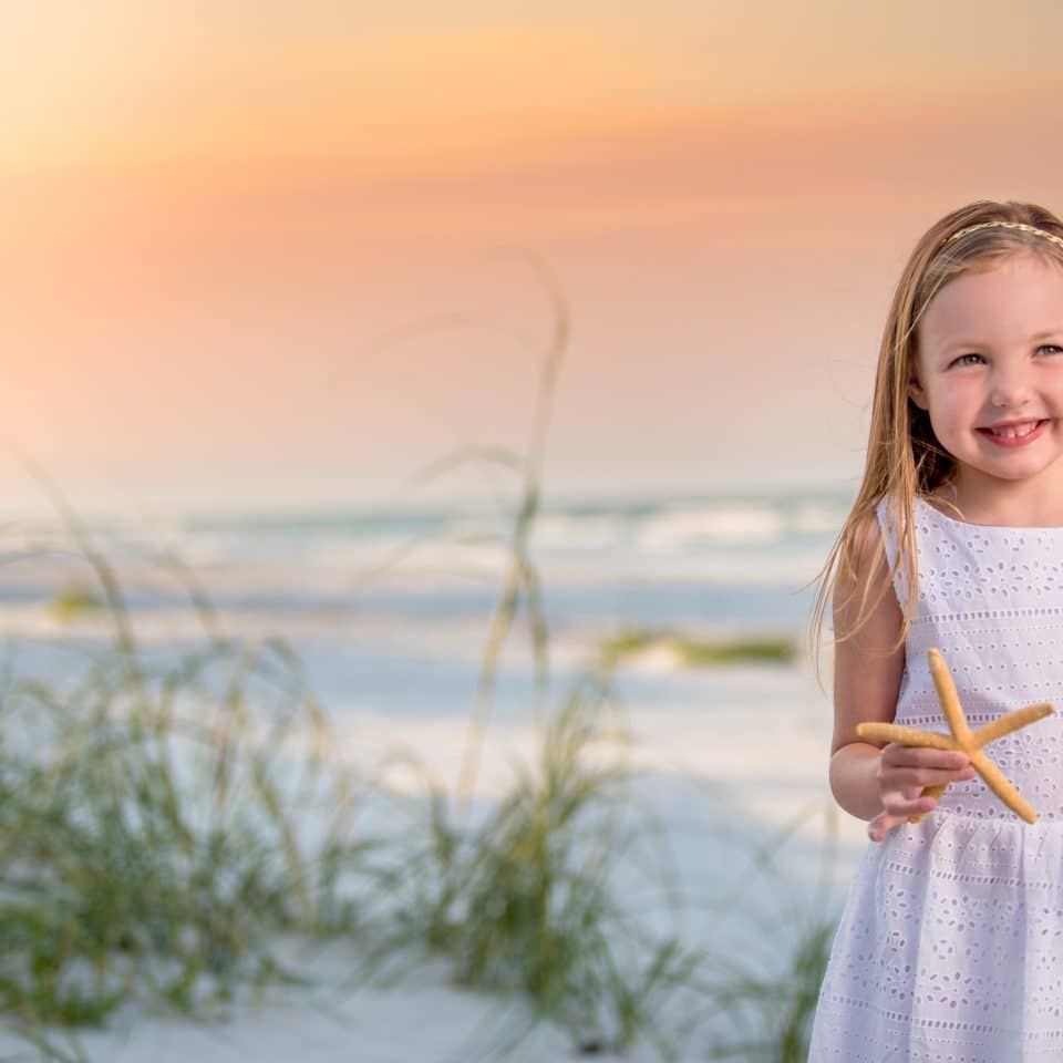 New Smyrna beach photographer captures a portrait of a child on new Smyrna beach at sunset holding a starfish