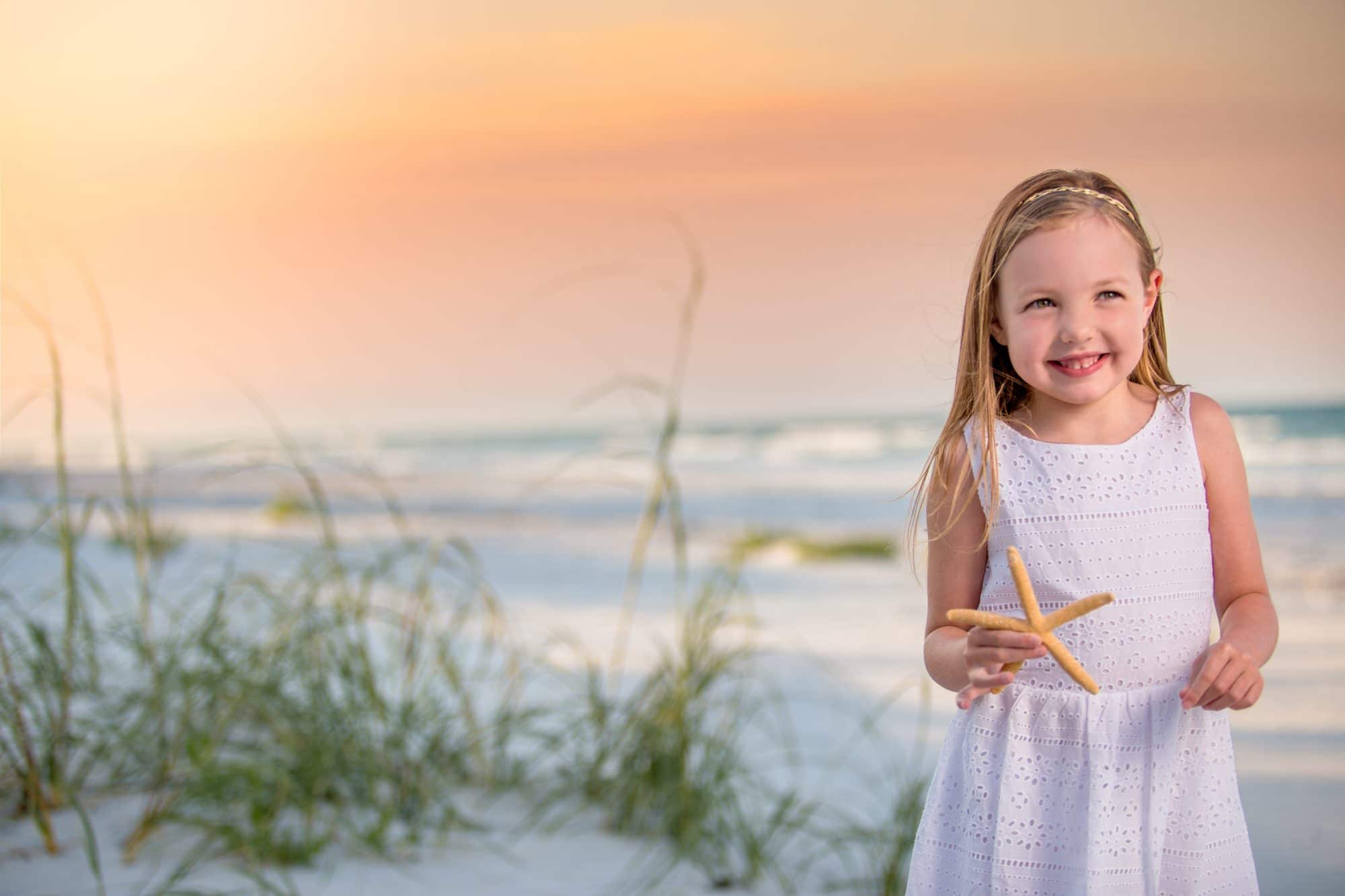 New Smyrna beach photographer captures a portrait of a child on new Smyrna beach at sunset holding a starfish