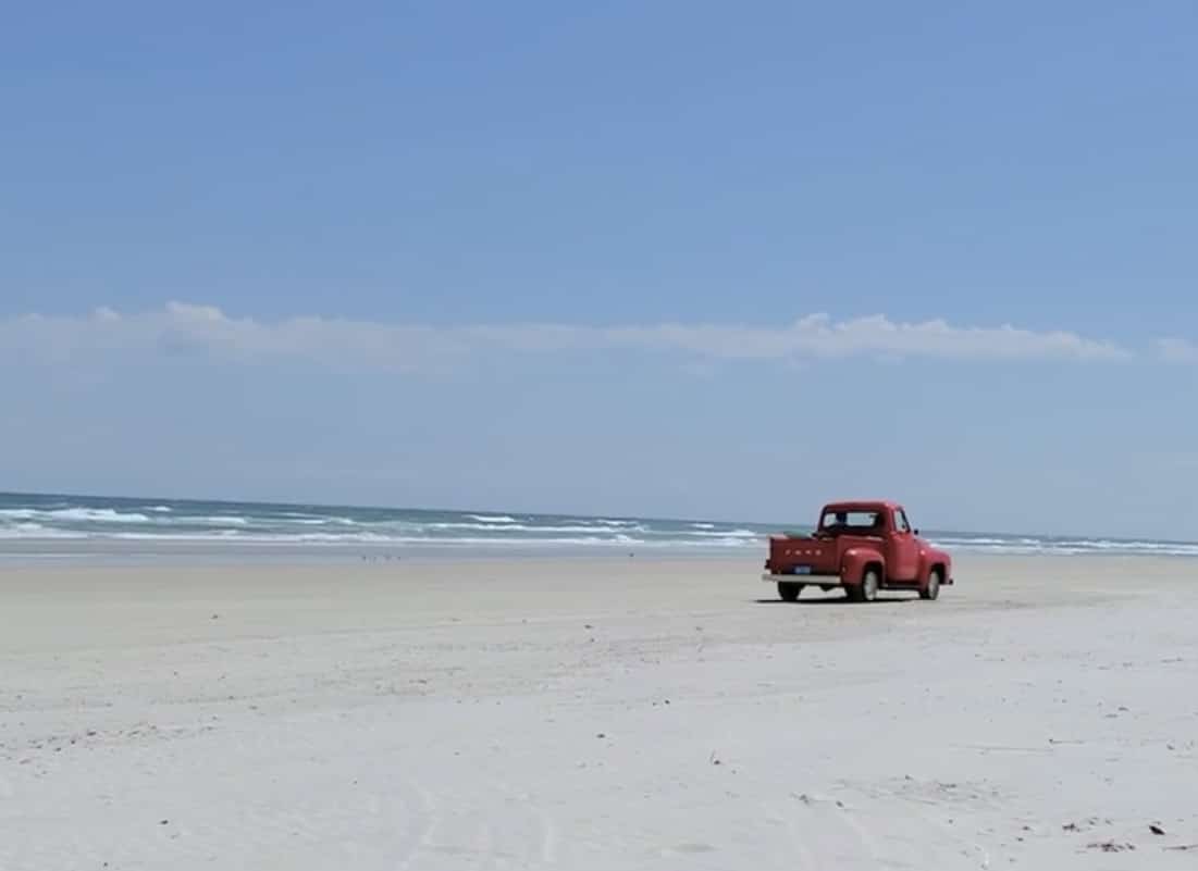 beach driving in New Smyrna Beach red vintage truck driving on beach