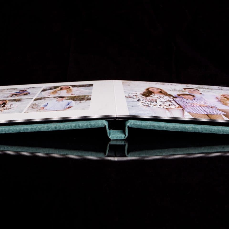 New Smyrna Beach photographer captures image of a photo album laying flat and open showcasing a beach portrait session in New Smyrna Beach with a black background