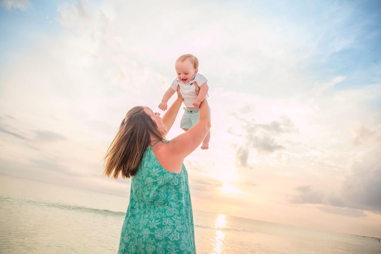 Lido Key photographer captures image of mom holding her baby up and playing on lido key beach at sunset