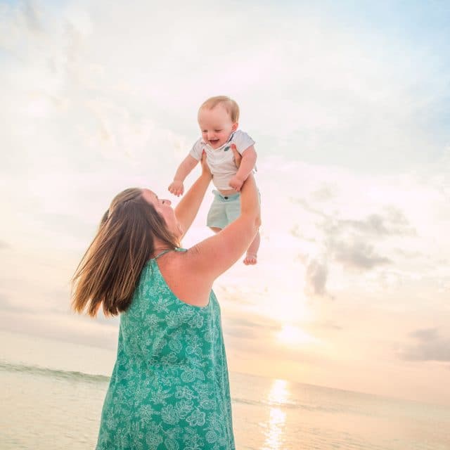 Lido Key photographer captures image of mom holding her baby up and playing on lido key beach at sunset