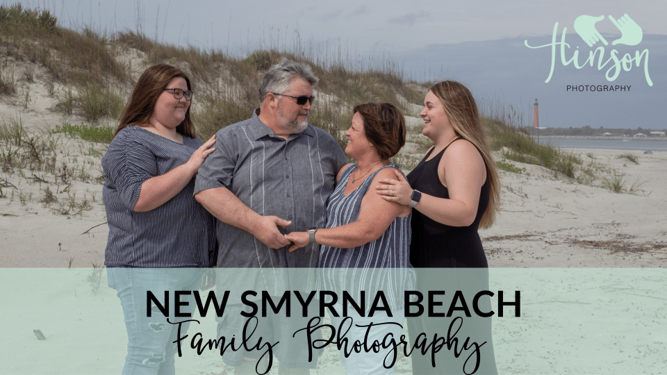 New Smyrna Beach family photography with sand dunes in the background, red lighthouse and a little bit of the ocean showing. Family of four with two adult daughters.