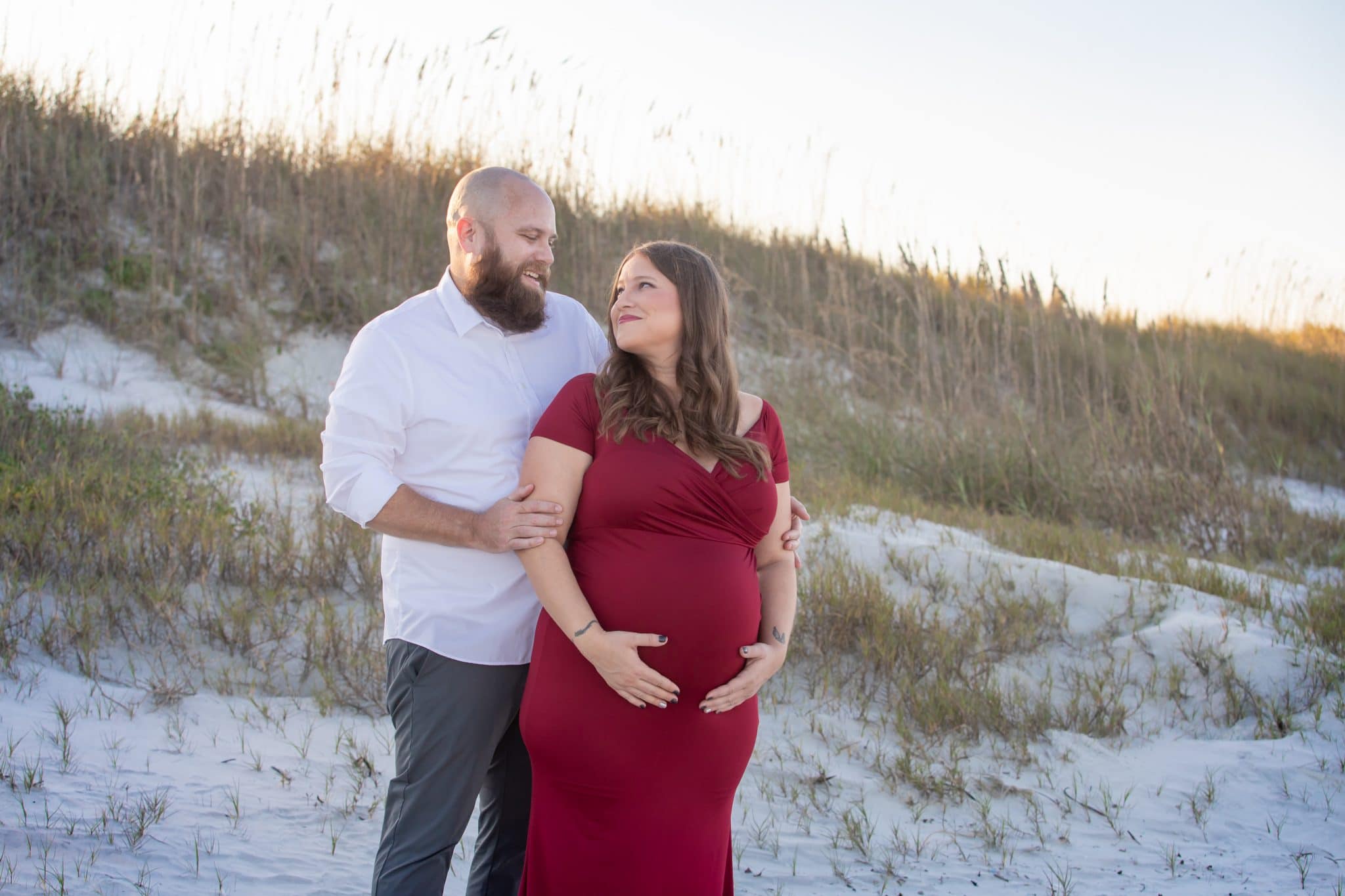 Maternity portrait of a couple at smyrna dunes park in New Smyrna Beach, FL at sunset with sand dunes in the 