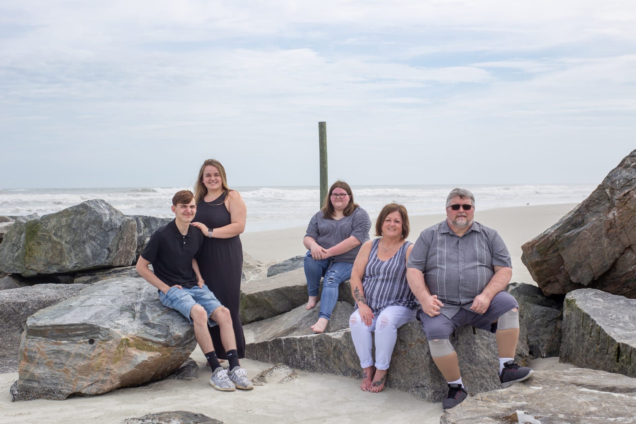 A family posing on a rock jetty in New Smyrna Beach for family beach photos 