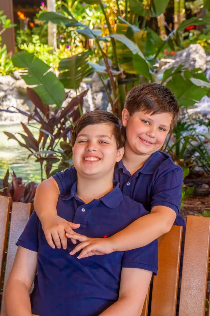 two kids pose for an Orlando photographer at Disney's Polynesian resort in front of the waterfall