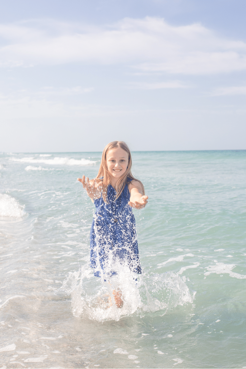 girl on beach playing in water for family beach photography session