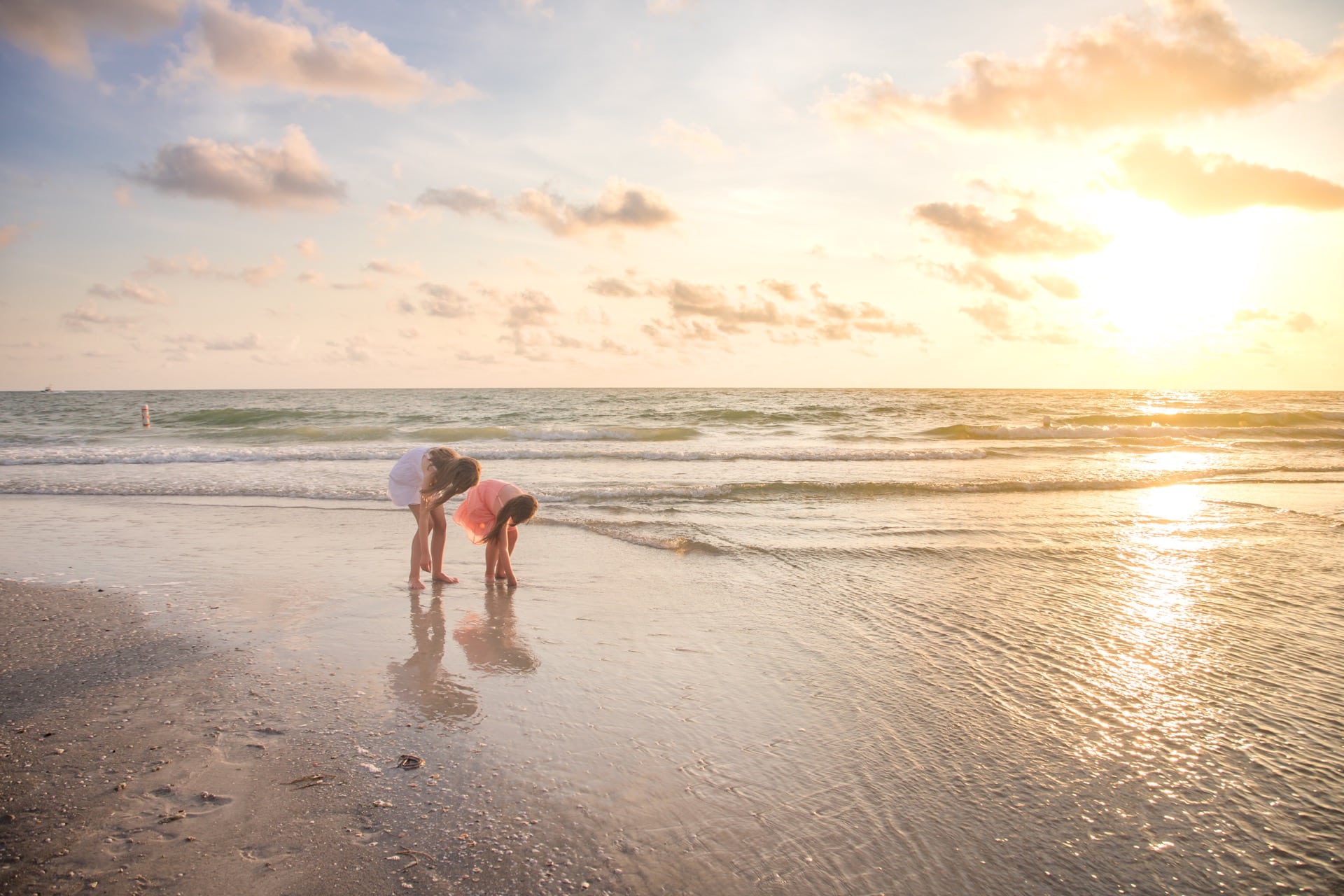 clearwater photographer captures photo of two sisters finding seashells at sunset at sand key park in clearwater fl