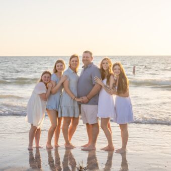 Clearwater Beach family photography of a family of 6, parents and their 4 daughters posing at sunset with the gulf coast in the background