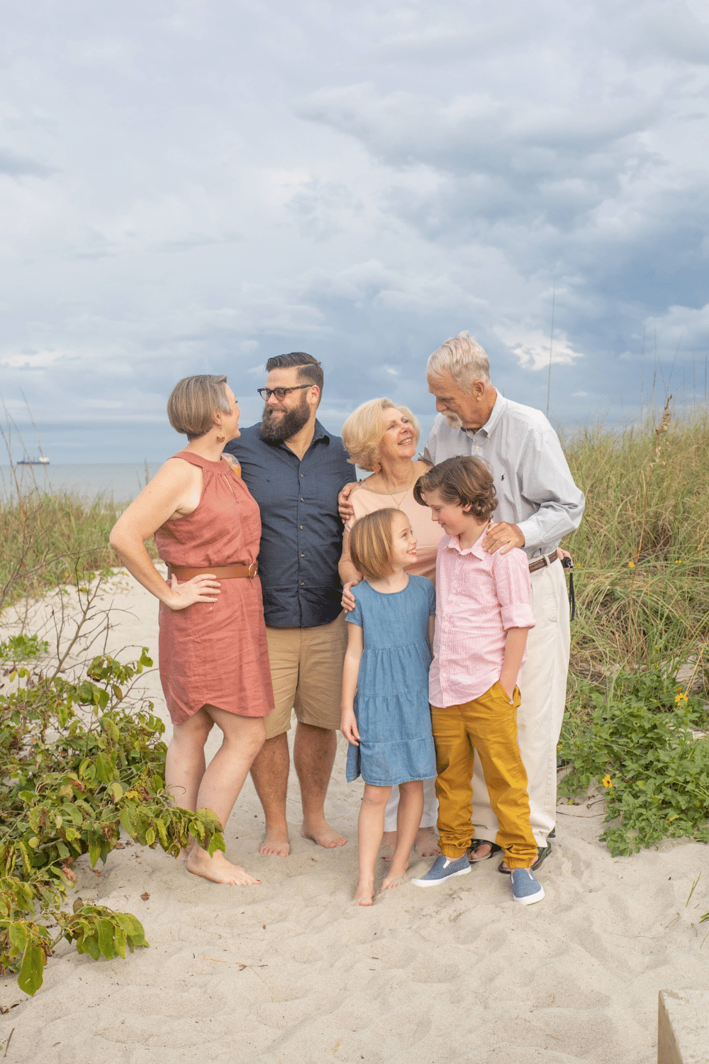 cocoa beach family photoshoot with a family of 4 and their grandparents. They re wearing Blue and pink outfits for beach photos.