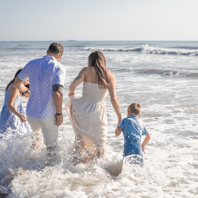 family of 4 playing in the waves for a beach photoshoot by a cocoa beach photographer