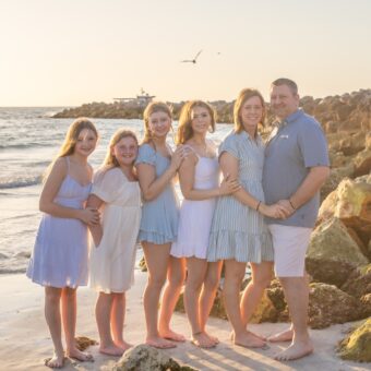 clearwater photographer captures portrait of a family of 6 with a rock jetty in the background at sand key park