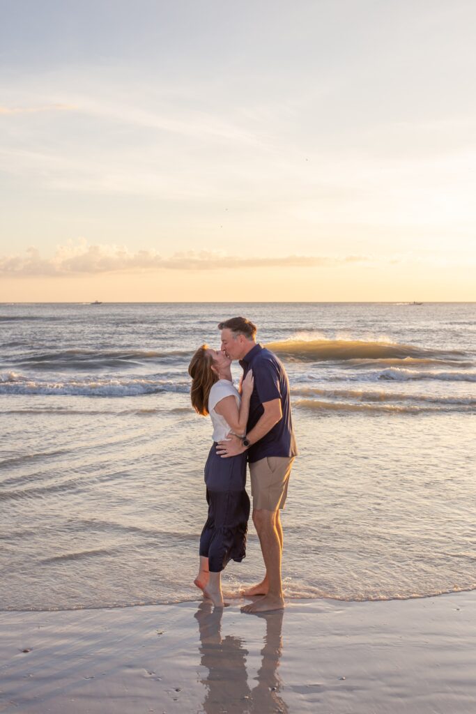 a couple kisses on the beach at sunset for a family photoshoot in siesta key fl