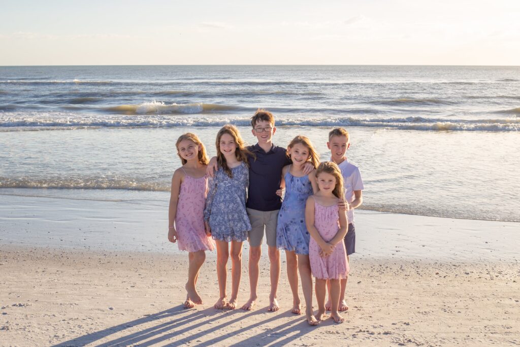 A Siesta Key Beach family photographer photographs the grand kids posing for a group photo on the beach