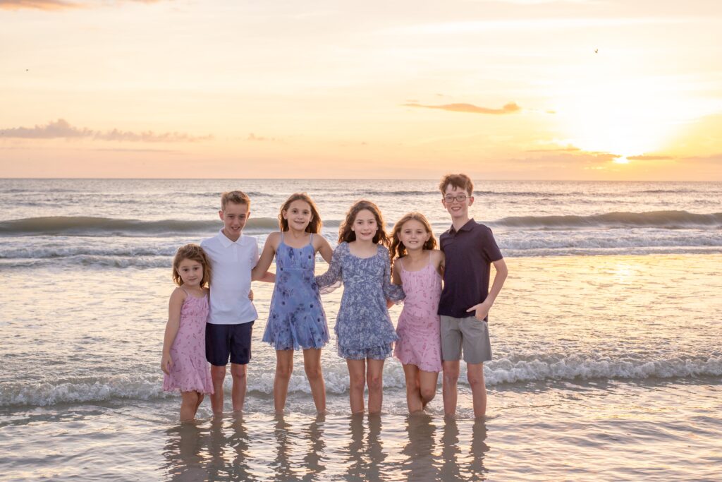 siesta key family photoshoot with cousins on the beach at sunset standing in the water